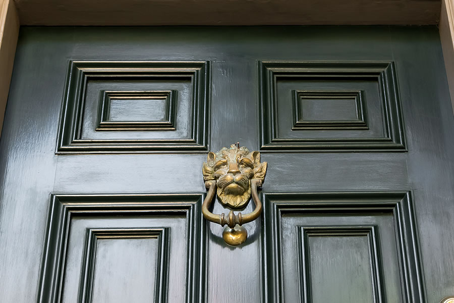 Grüne historische Tür mit goldfarbenem Löwenkopf als Türklopfer