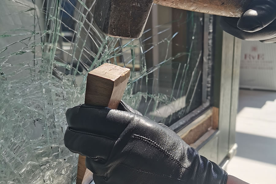 Detail Hände mit Hammer und Keil zerstören Fensterscheibe